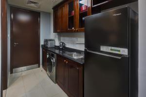 a kitchen with a black refrigerator and a sink at Kay Homes Royal Studio in Ras al Khaimah