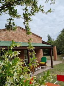 ein Backsteinhaus mit einer Terrasse und einem grünen Stuhl in der Unterkunft Cabanias El Aguaribay in San Javier