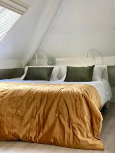 een slaapkamer met een groot bed met een bruine deken bij Cottage Uylenhorst, De Witte Bergen 34 in IJhorst