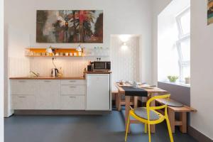 uma cozinha com uma mesa e duas cadeiras amarelas em Stylish holiday Art apartment - wifi & great location em Budapeste