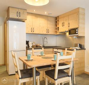 een keuken met een houten tafel met stoelen en een koelkast bij Gîte de la Loza in Sollières-Sardières