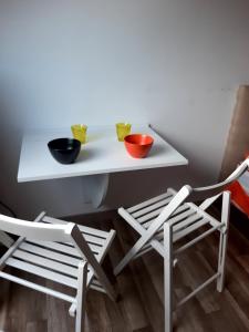 two bowls on a white table with two chairs at Comme chez vous in Le Torp-Mesnil