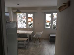 eine Küche mit einem Tisch, einem Tisch und 2 Fenstern in der Unterkunft Catedral Sur departamento en Bariloche in San Carlos de Bariloche