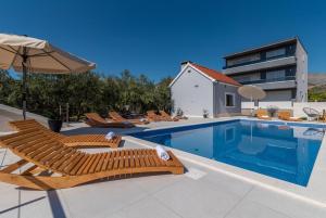 ein Swimmingpool mit Liegestühlen und einem Sonnenschirm in der Unterkunft Villa Dalmata in Trogir