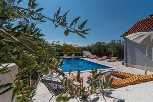 ein Schwimmbecken mit Stühlen und einem Sonnenschirm in der Unterkunft Villa Dalmata in Trogir