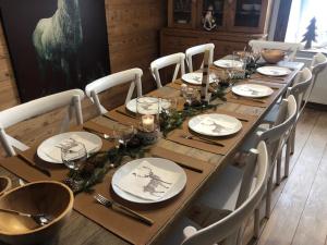 una larga mesa de madera con platos blancos y cubiertos en Le Valtinet, séjour esprit montagne, en Le Valtin