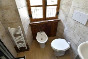 ein Bad mit einem WC, einem Waschbecken und einem Fenster in der Unterkunft Rustico nel Parco Nazionale in Ronco Canavese