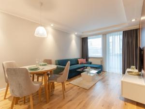 ein Wohnzimmer mit einem blauen Sofa und einem Tisch in der Unterkunft Apartament Premium Bliżej Morza in Kołobrzeg