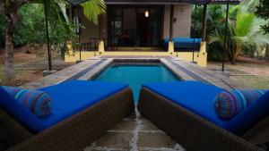 a swimming pool with blue cushions in front of a house at Mind Body and Soul in Dambulla