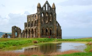 an old castle in a field with a pond at Endeavour Cottage Whitby sleeps 6 in Whitby