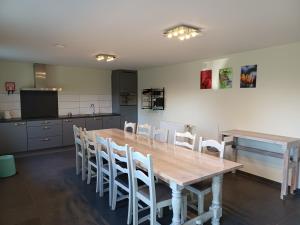 a kitchen with a wooden table and white chairs at de ploeg luxe in Bullange