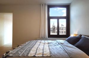 Un dormitorio con una cama grande y una ventana en Appartement et parking privatif le long de l Escaut, en Tournai