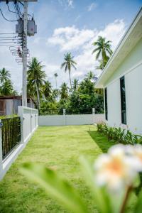 a backyard with a white fence and grass at บ้านคุณพระ แอท รพ.กรุงเทพ in Surat Thani