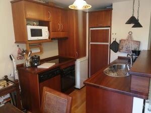 cocina con armarios de madera y microondas en Apartamento Sarrato IV de Sallent, en Sallent de Gállego