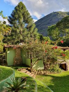 uma casa verde com uma montanha ao fundo em Pousada Paraíso Açú em Itaipava