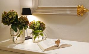 une table avec deux vases, un livre et des fleurs dans l'établissement Hotel Sant'Andrea, à Santa Margherita Ligure