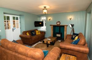 a living room with brown couches and a fireplace at Netherdale House & The Coach House in Turriff
