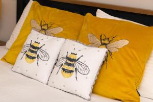 4 almohadas con abejas pintadas en una cama en Netherdale House & The Coach House, en Turriff