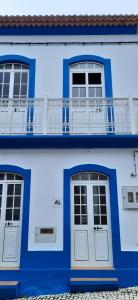 ein blaues Gebäude mit zwei Türen und einem Balkon in der Unterkunft Moradia Machado in Topo