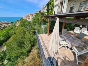 um pátio com um guarda-sol e cadeiras e o oceano em Il Nido - Casa Vacanze sulla Costa dei Trabocchi em San Vito Chietino