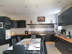 a kitchen with black cabinets and a table in it at Chambres d'hôtes Natacha et Franck in Labastide-Rouairoux