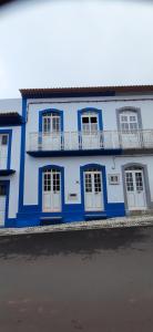 ein blaues Gebäude mit weißen Türen und einem Balkon in der Unterkunft Moradia Machado in Topo