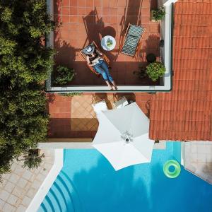 eine Aussicht auf einen Pool mit einem Regenschirm und einem Mann in der Unterkunft Villa Pefki in Chania