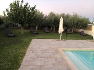 a patio with an umbrella and a swimming pool at Casa Zagara in Avola