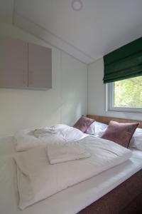 duże białe łóżko w pokoju z oknem w obiekcie Racoon - Außergewöhnliches Tinyhauserlebnis beim Reptilienzoo Reptilium w mieście Landau in der Pfalz