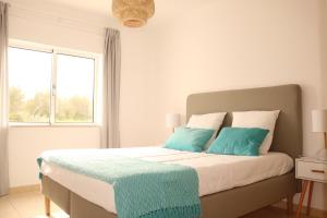 - une chambre avec un lit doté d'oreillers bleus et d'une fenêtre dans l'établissement Casa do Mar - Apartamento com vista Ria e Mar, à Fuzeta