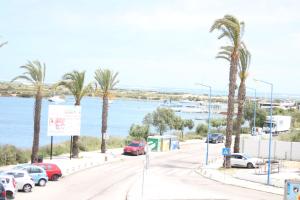 uma rua com carros estacionados numa estrada com palmeiras em Casa do Mar - Apartamento com vista Ria e Mar na Fuzeta