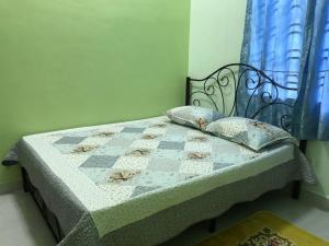 a bed with a quilt and pillows in a bedroom at Tok Chik Homestay in Kampong Lubok Bedil