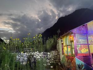 a building with a colorful window in a field of flowers at Breathe Inn in Kasol