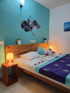 Schlafzimmer mit einem Bett mit blauer Wand in der Unterkunft Faima Fishing Lodge at Daravandhoo in Baa-Atoll