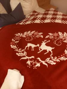 a bed with a red blanket with white patterns on it at Haus Höllwart in Sankt Johann im Pongau