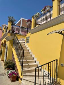 um edifício amarelo com escadas e flores nas varandas em Pauli'S Holiday House em Monserrato