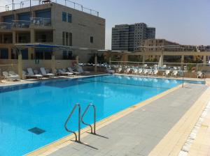 a large swimming pool with chairs and a building at Last Minute Herzliya in Herzliya