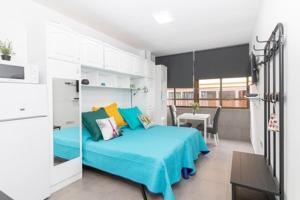 - une chambre avec un lit avec des draps bleus et une table dans l'établissement Estudio W&G Las Canteras con bonitas vistas al mar, à Las Palmas de Gran Canaria