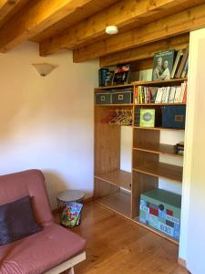 ein Wohnzimmer mit Sofa und Bücherregal in der Unterkunft Appartement dans chalet avec jardin, vue montagne in Aucun