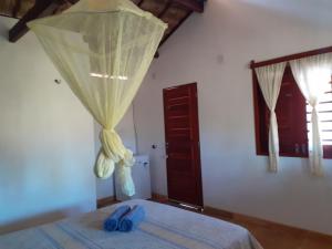 a bedroom with a bed with blue slippers on it at Chalés Bons Ventos - Icaraizinho in Icaraí