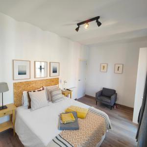 una camera con un grande letto bianco e una sedia di Bright flat next to Stadium y La Fira a Hospitalet de Llobregat