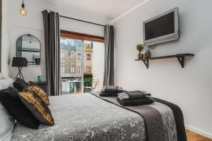 a bedroom with a bed and a flat screen tv at Avenue View Rooms in Porto