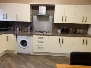 a kitchen with white cabinets and a washing machine at S&Ks in Troed-y-rhiw