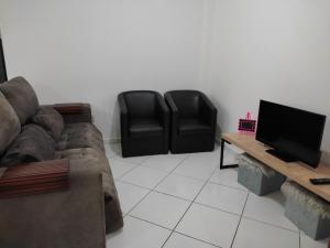 - un salon avec un canapé et deux fauteuils noirs dans l'établissement Temporada balneário camboriu, à Balneário Camboriú