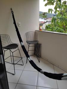 a hammock on a balcony with chairs and a window at Temporada balneário camboriu in Balneário Camboriú