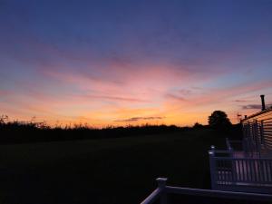 a sunset with a white chair in a yard at Luxury Holiday Home in Anderby Creek in Anderby