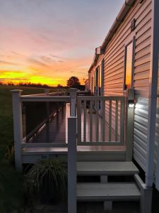 a house with a deck with a sunset in the background at Luxury Holiday Home in Anderby Creek in Anderby