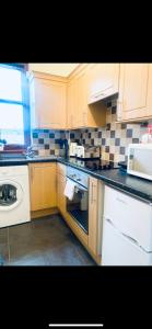 a kitchen with wooden cabinets and a white stove top oven at Largs Holiday Apartment in Largs