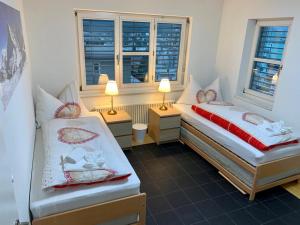 a bedroom with two beds and two windows at Ferienwohnung Rütiboda 8-10 Personen in Davos