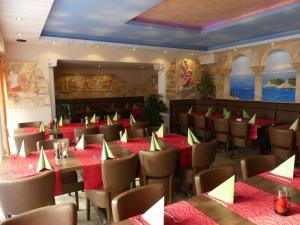 um restaurante com mesas e cadeiras com guardanapos vermelhos e verdes em Hotel Akropolis em Herford